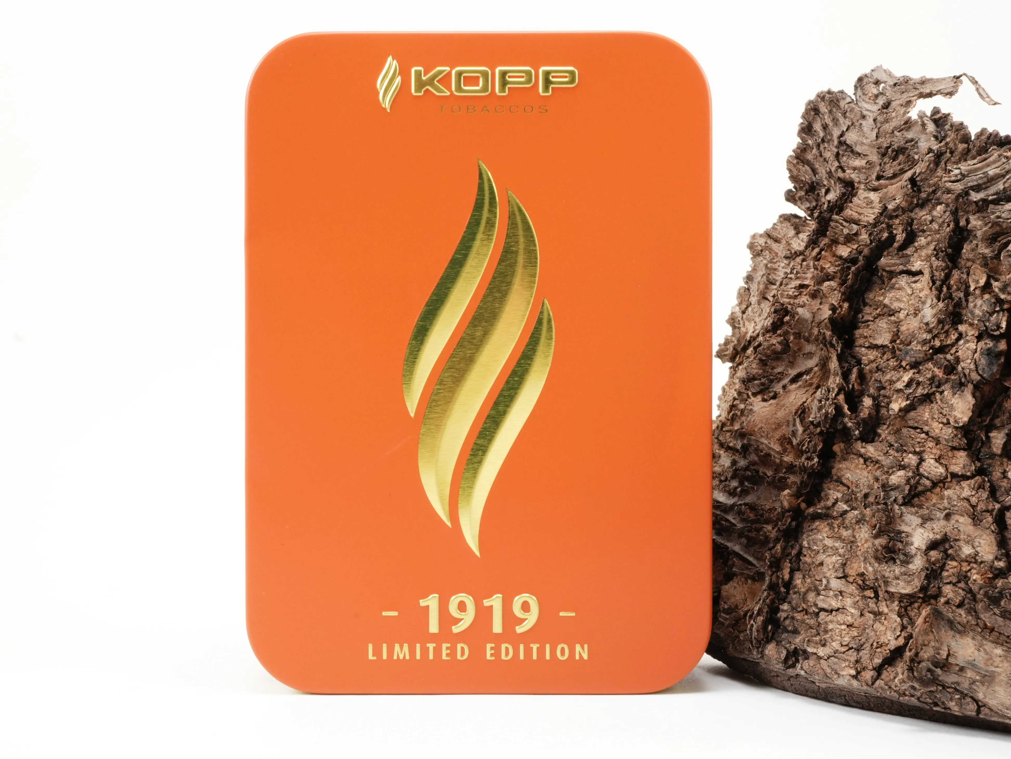 Rechteckige orangefarbene Kopp 1919 Limited Edition 2027 Schmuckdose mit vergoldeter Flammen-Prägung vor Rindenhintergrund – Titelbild