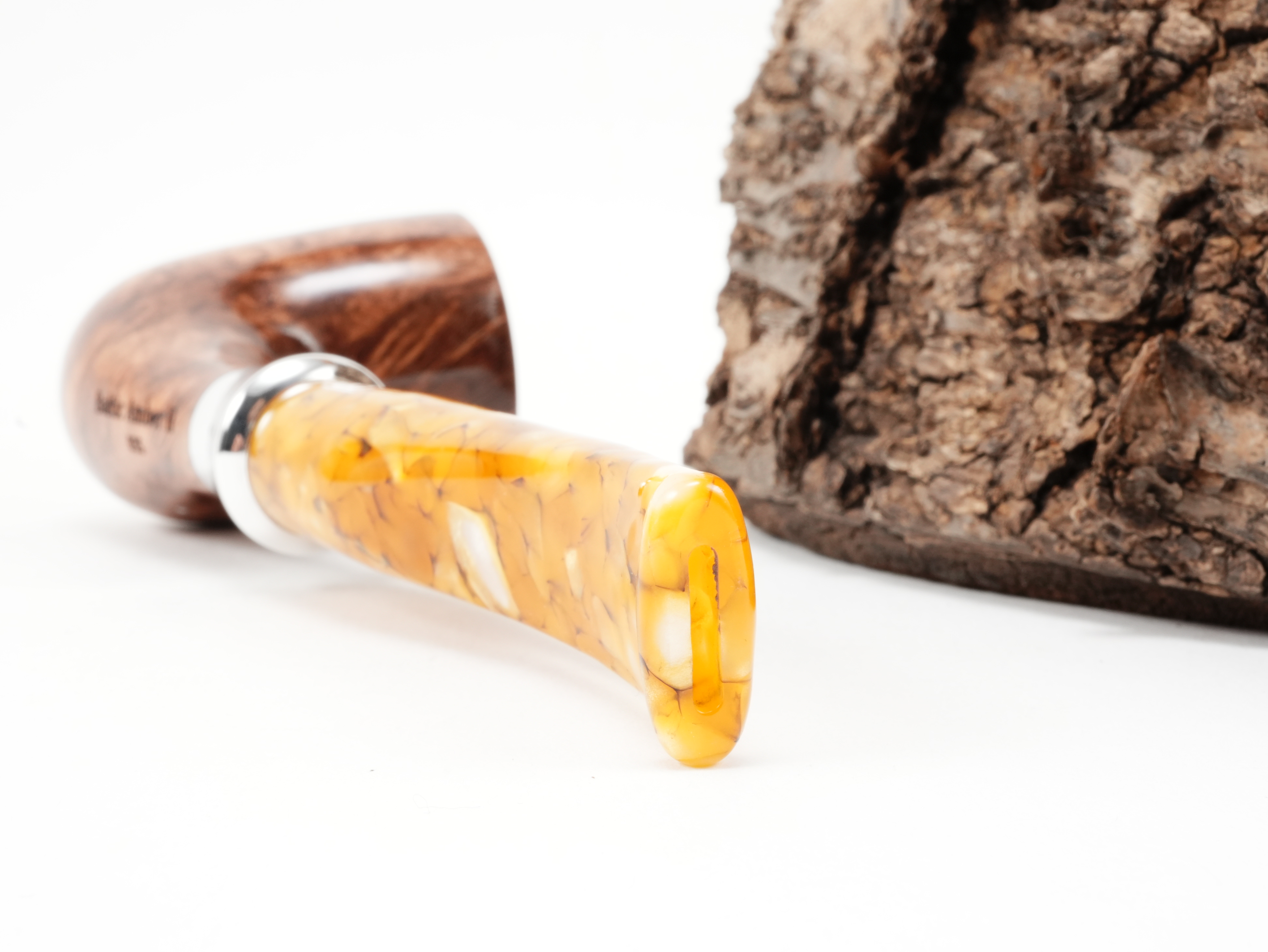 Nahaufnahme des gebogenen bernsteinfarbenen Acrylmundstücks der db Design Berlin Baltic Amber II 035 Pfeife mit trichterförmigem Metallring und Bissstelle von hinten