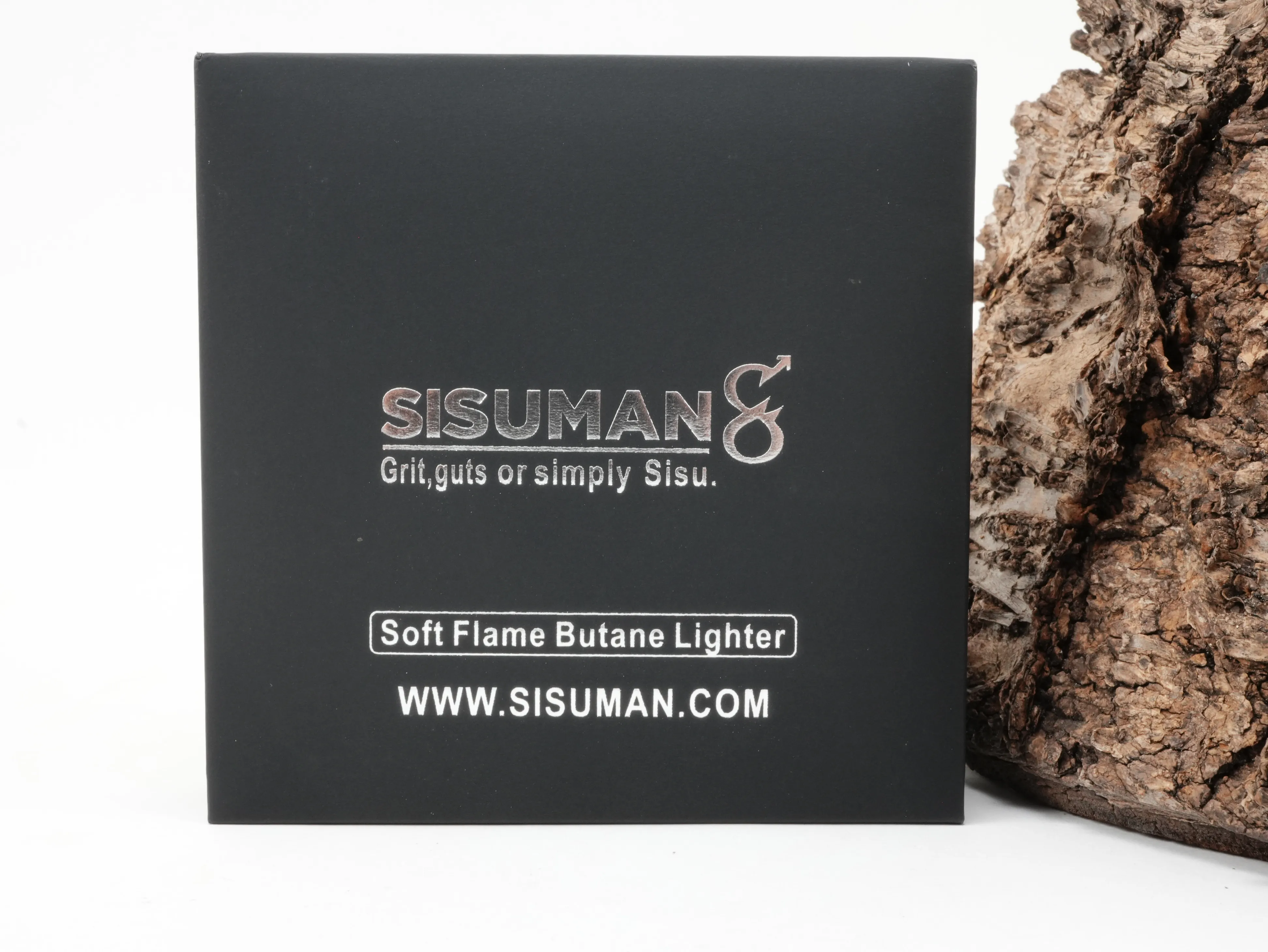 Mattschwarze Sisuman Geschenkschachtel für das Soft Flame Butan Feuerzeug vor Rindenhintergrund
