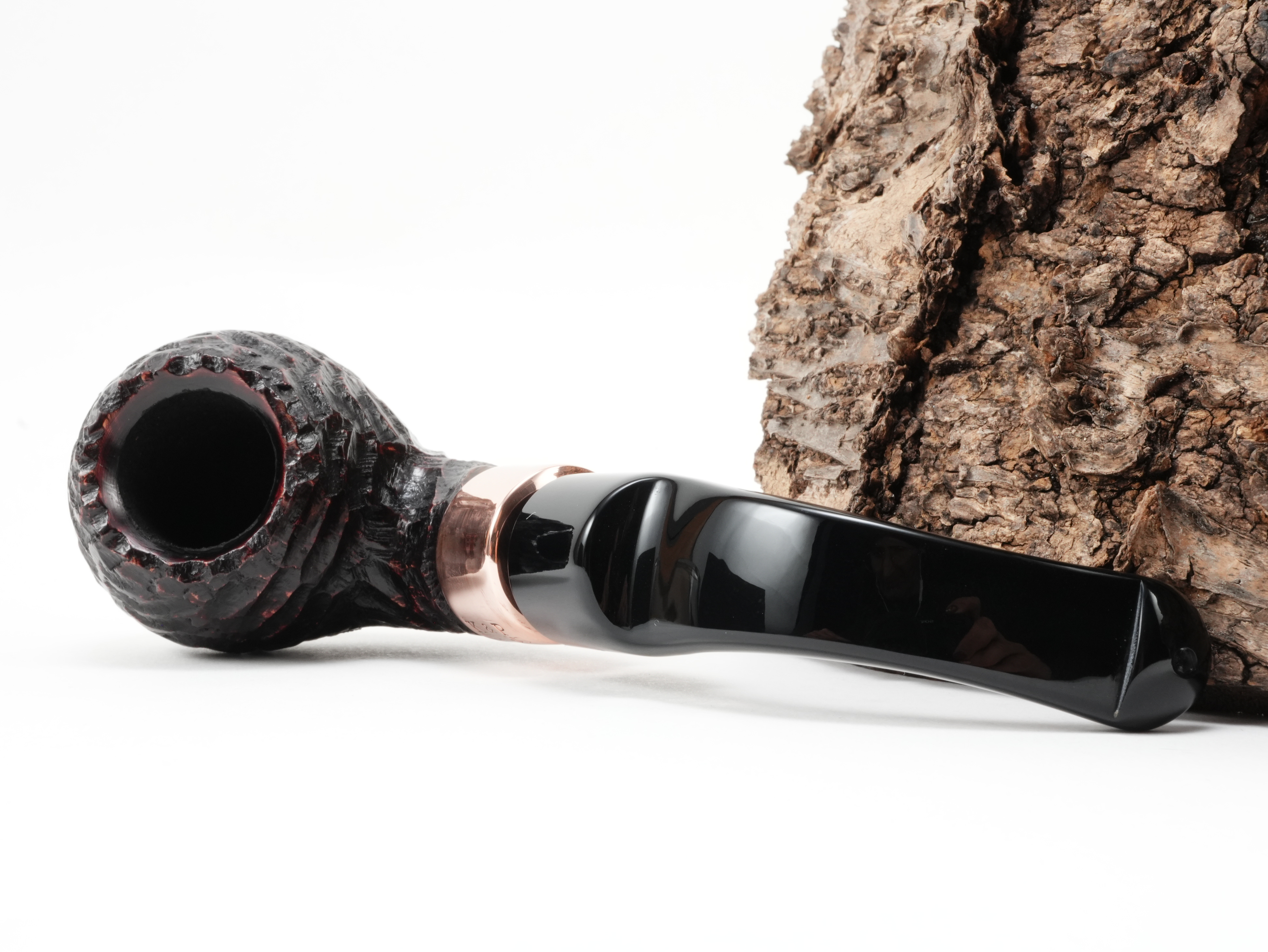 Peterson Christmas 2026 Rustic 3s Bent Ball Pfeife liegend von schräg hinten mit Fokus auf die glänzende K&P Kupferapplikation am Holm