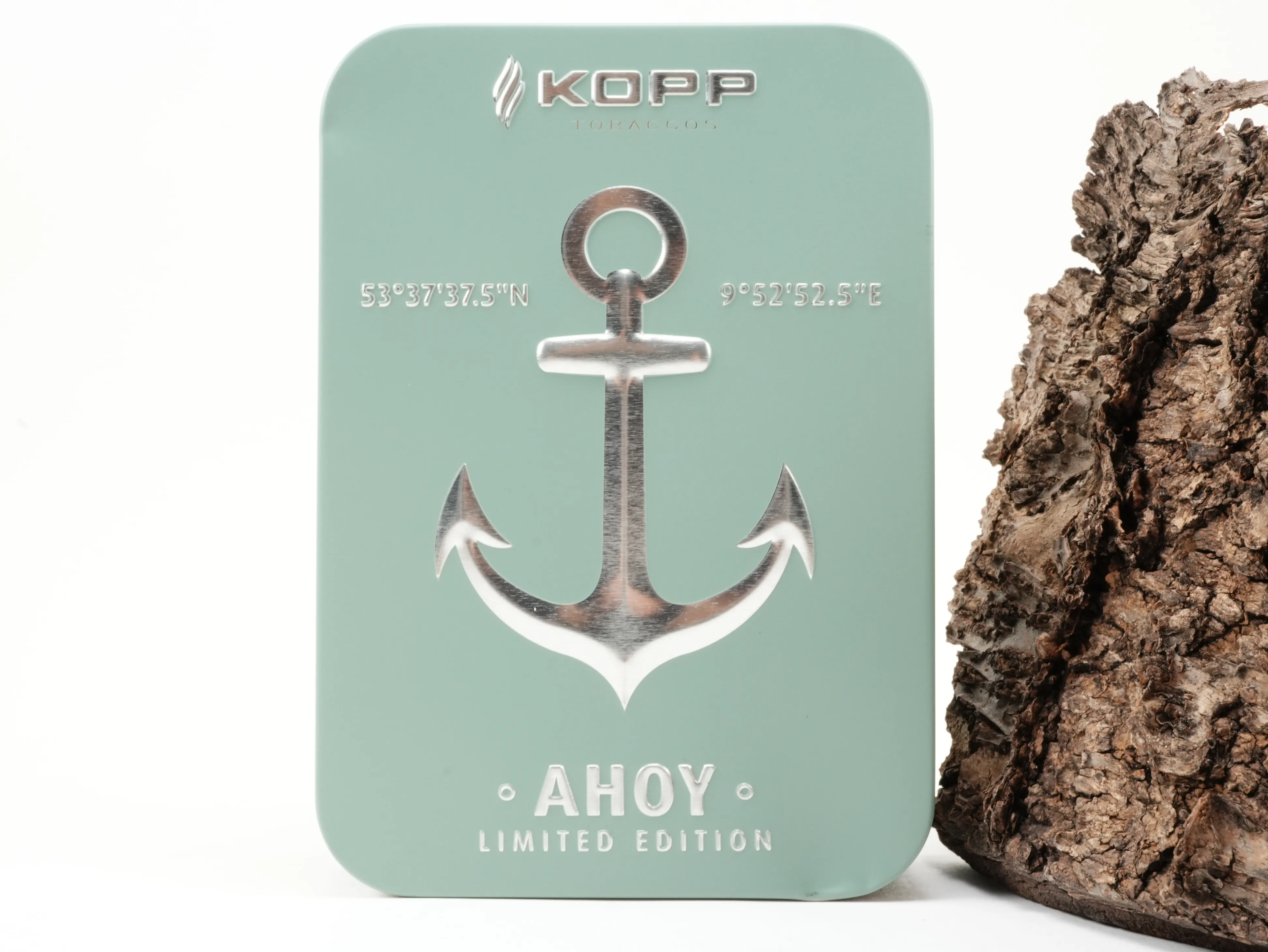 Rechteckige sage-grüne Kopp AHOY Limited Edition 2027 Schmuckdose mit silberner Anker-Prägung und Koordinaten vor Baumrinde – Titelbild
