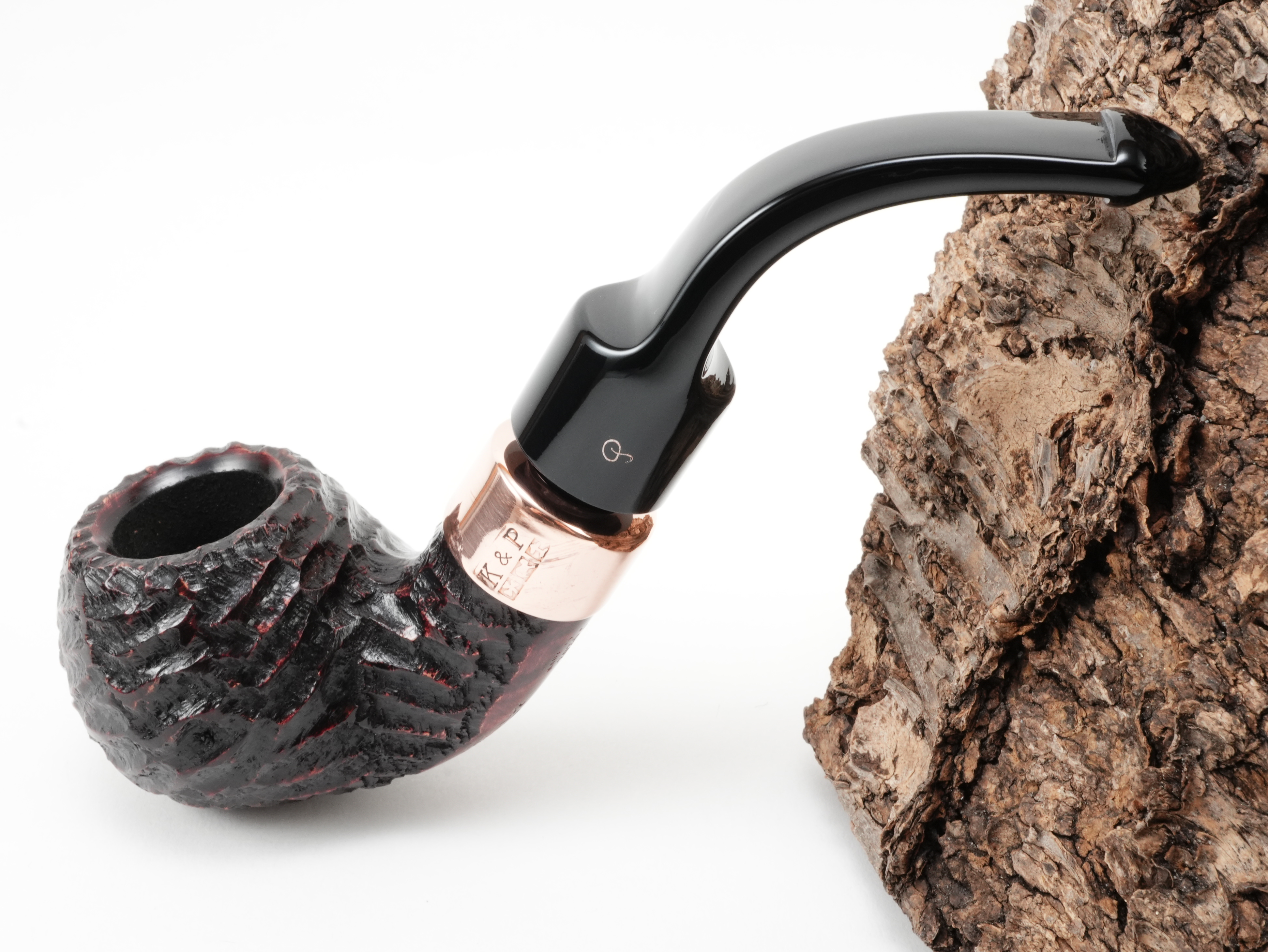 Rotbraun rustizierte Peterson Christmas 2026 Rustic 3s Pfeife Bent Ball mit K&P Kupferring und kupferfarbenem P-Logo am Lippenbissmundstück – Titelbild schräg von oben