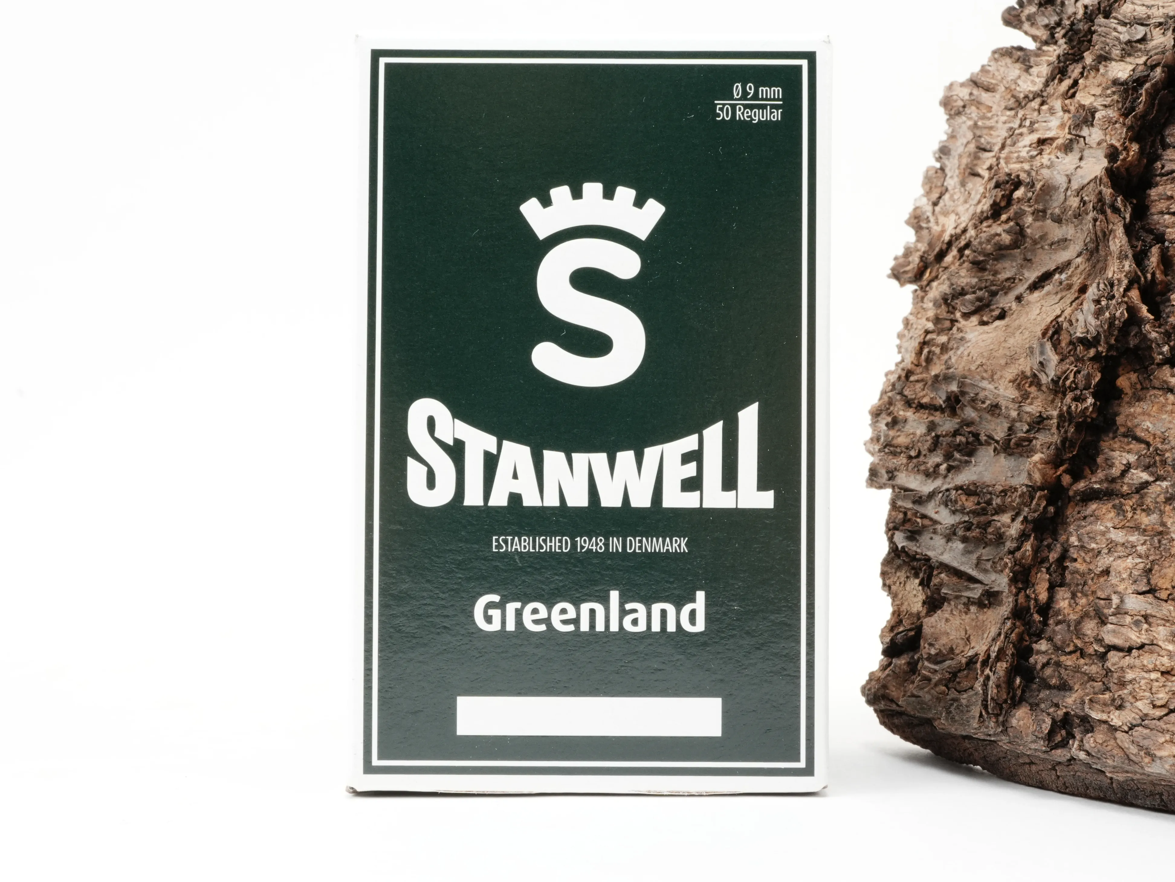 Dunkelgrüne Verpackung der Stanwell Greenland 9mm Aktivkohlefilter 50 Stück mit Kronen-Logo vor Rindenhintergrund – Titelbild