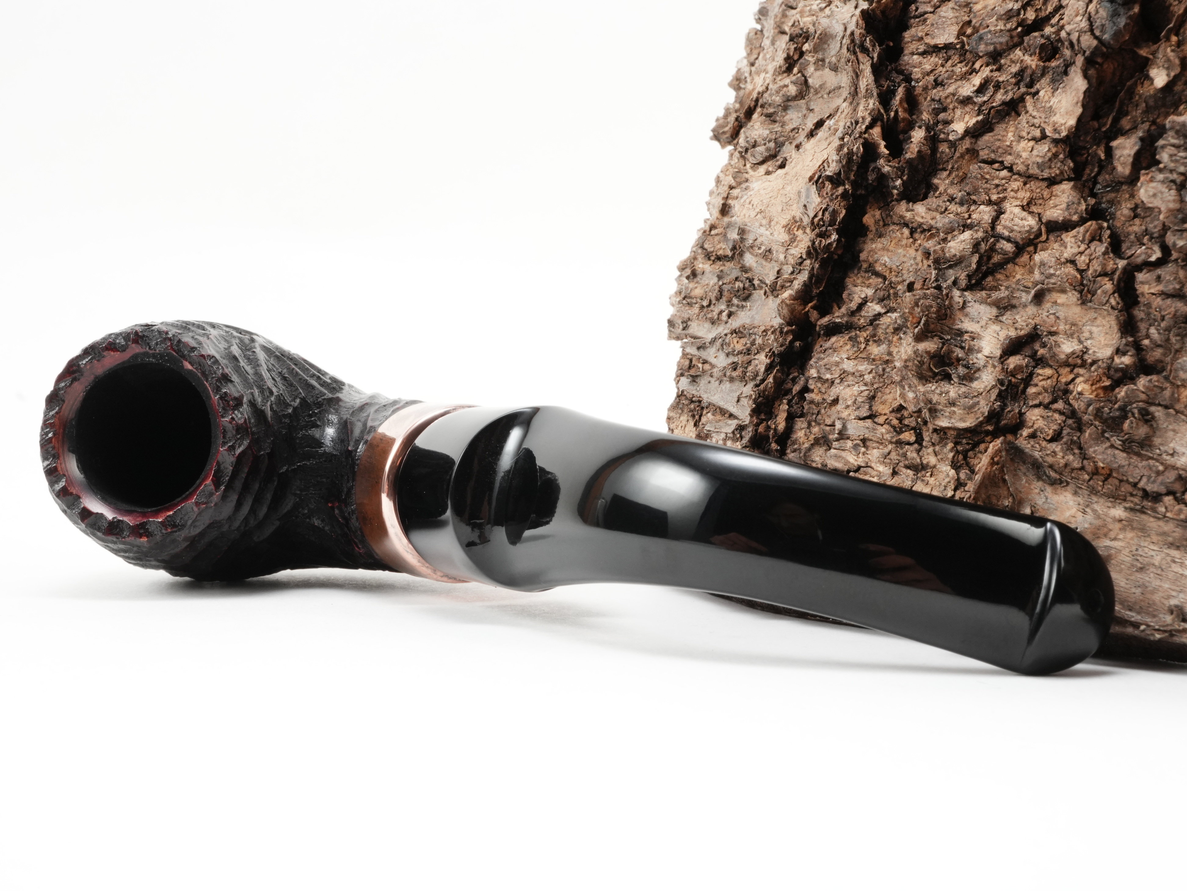 Peterson Christmas 2026 Rustic 11s Bent Classic Pfeife liegend von schräg hinten mit Fokus auf die glänzende K&P Kupferapplikation am Holm