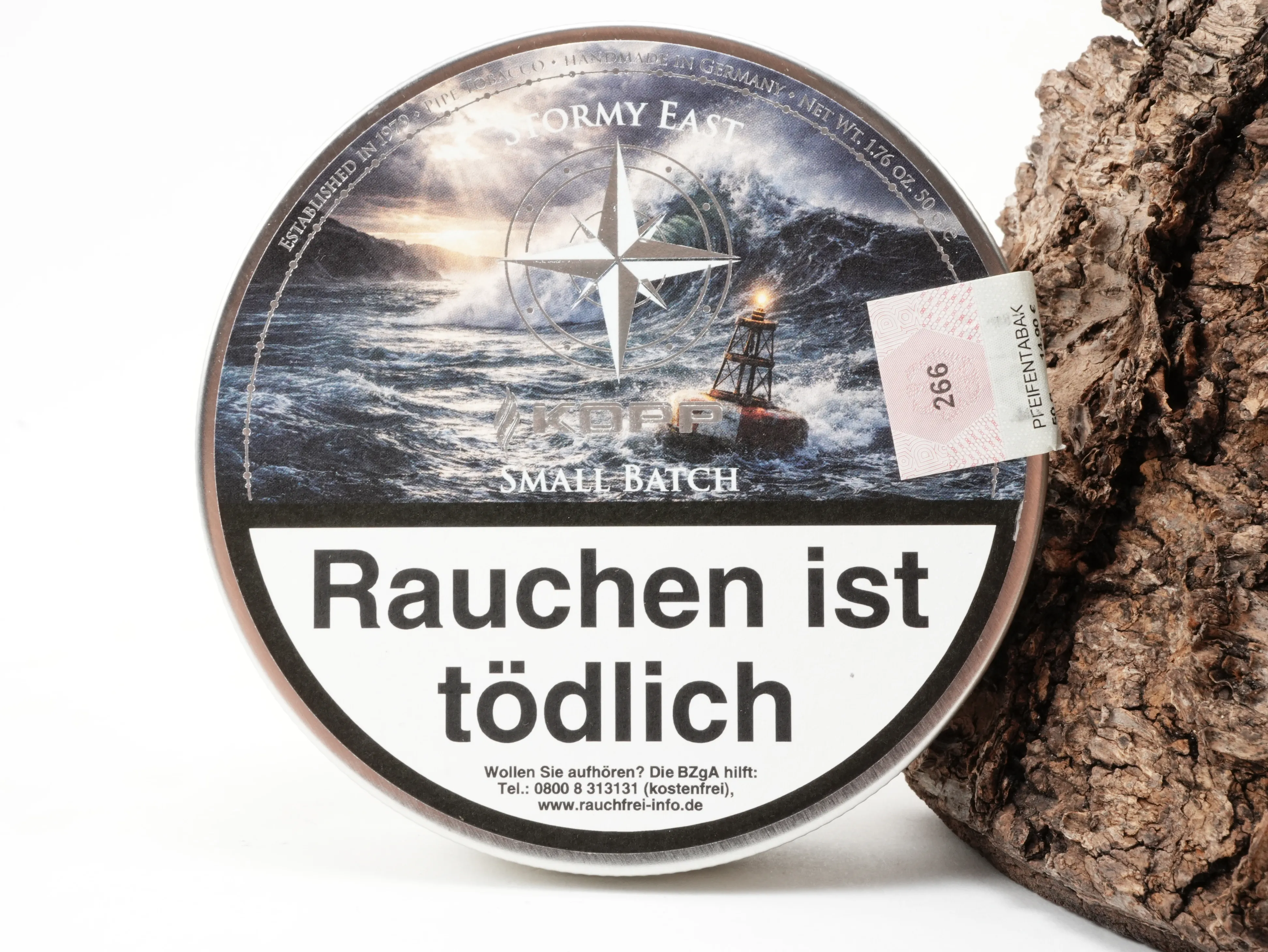 Runde Kopp Tobaccos Small Batch Stormy East Tabakdose mit Kompass-Motiv vor Rindenhintergrund – Titelbild