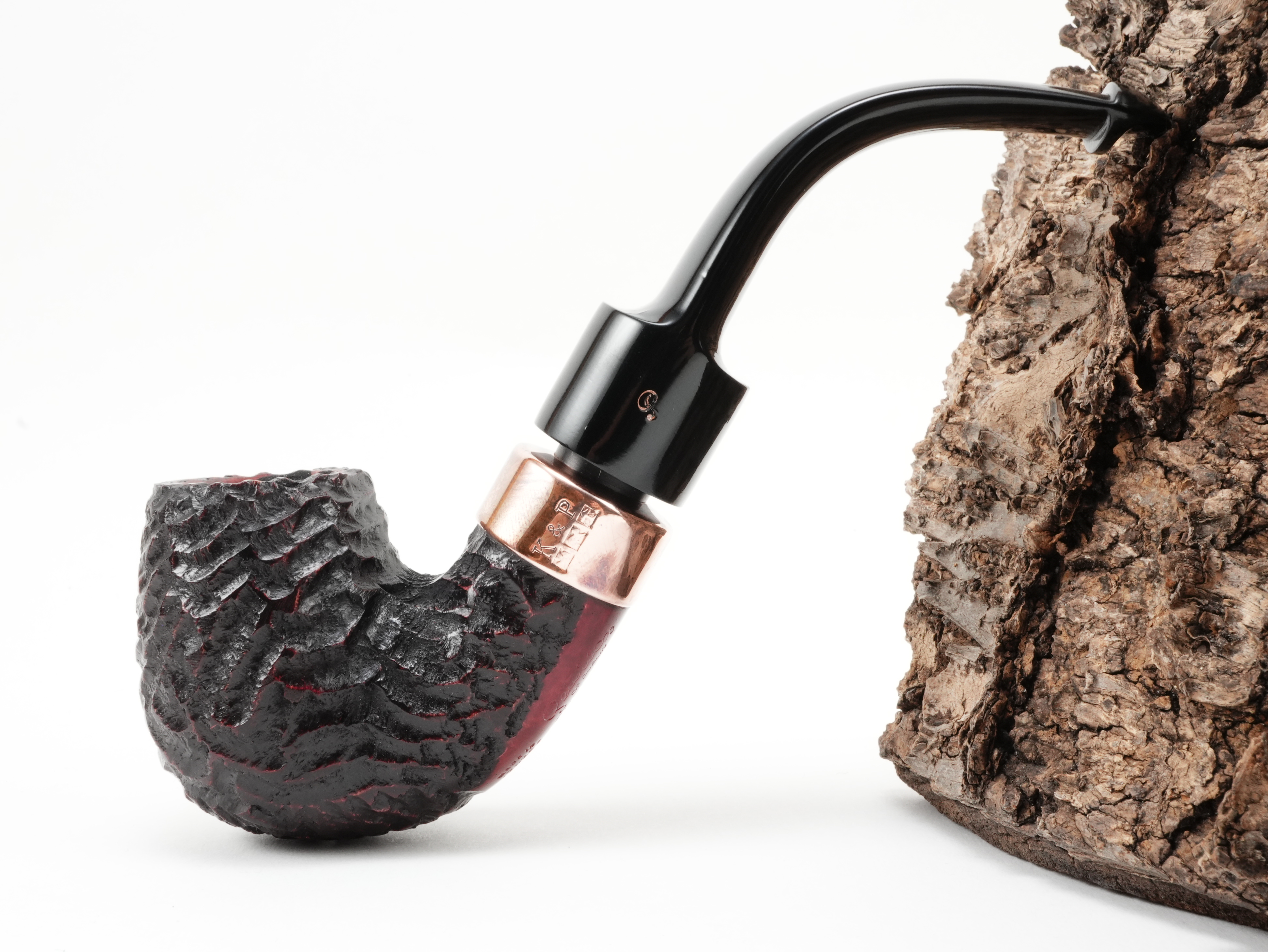 Seitenansicht der gebogenen Peterson Christmas 2026 Rustic 11s System-Pfeife mit dunkler Rustizierung, geprägtem K&P Kupferring und Peterson P-Logo
